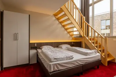 a bedroom with a bed and a staircase at Hotel De Boskar Pelt in Pelt