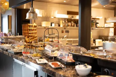 a kitchen with many dishes on a counter in a restaurant at Hotel De Boskar Pelt in Pelt