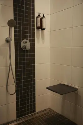 a bathroom with a shower with a black and white tiles at Hotel De Boskar Pelt in Pelt
