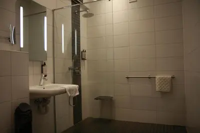 a bathroom with a sink and a shower with a mirror at Hotel De Boskar Pelt in Pelt