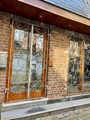 two iron gates on the side of a brick building at Aux portes du marché in Verviers