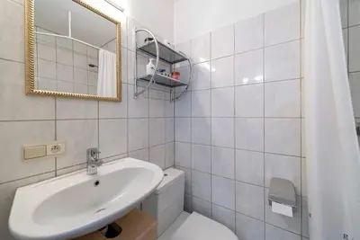 a bathroom with a sink and a toilet and a mirror at Tweekamer Apartement in Dilsen-Stokkem