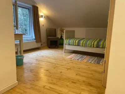a bedroom with a bed and a wooden floor at Tweekamer Apartement in Dilsen-Stokkem