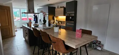 a kitchen with a wooden table and some chairs at Comme chez Soi in Liège