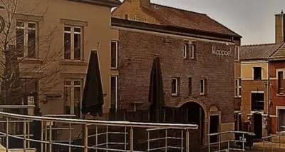 a brick building with umbrellas in front of it at Klappoel - by Cafe Rene Borgloon in Borgloon