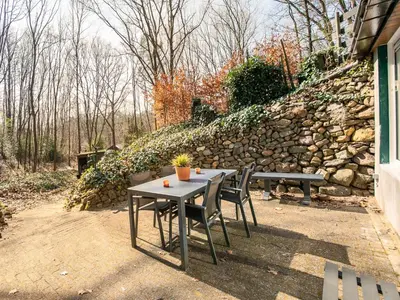 a table and chairs in front of a stone wall at Holiday Home in Lanklaar near Forest Trails in Lanklaar