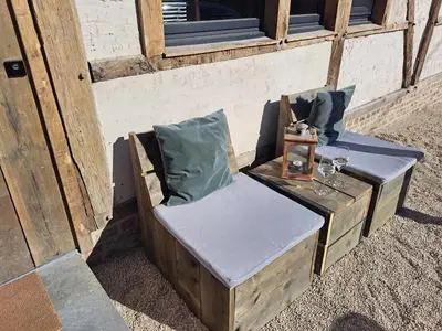 a wooden chair sitting outside of a building at Hoeve BôThé - B&B in Alken