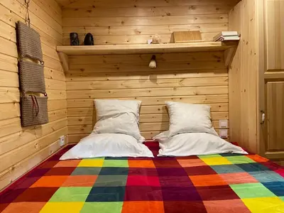 a bed in a wooden room with a colorful blanket at Pipowagen Harambé in Lanaken