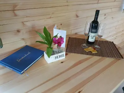 a table with a bottle of wine and a book and flowers at Pipowagen Harambé in Lanaken