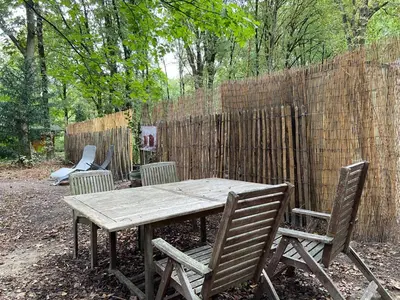 a wooden table with chairs and a fence at Pipowagen Harambé in Lanaken