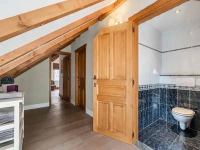 a bathroom with a toilet and a wooden door at Farmhouse including studio with Garden in Alken