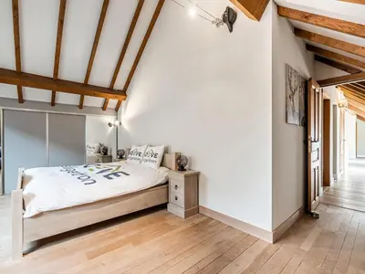 a bedroom with a bed with white walls and wooden floors at Farmhouse including studio with Garden in Alken