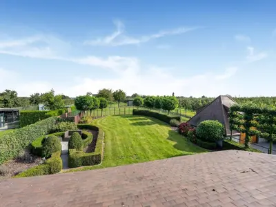 a view of a garden with hedges and bushes at Farmhouse including studio with Garden in Alken