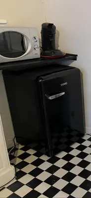 a microwave sitting on top of a black refrigerator at La petite maison de l'impasse in Liège
