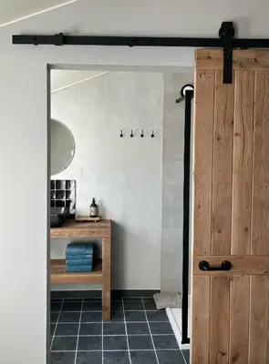 a bathroom with a mirror and a wooden door at Huisje Emma in Tongeren