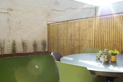 a room with a table and chairs and a fence at Maison Magnifiek in Hasselt