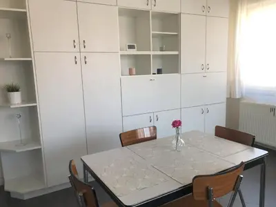 a dining room with a table and white cabinets at Appartement confortable proche centre et idéal pour ULiège Sart Tilman in Liège