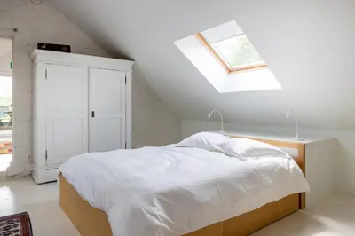 a white bedroom with a bed and a skylight at Land van Engelingen in Helshoven