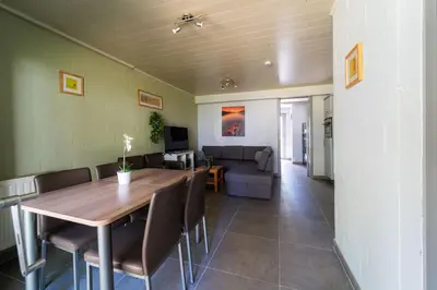 a dining room with a table and a couch at Acacia 8 Hengelhoef in Houthalen-Helchteren