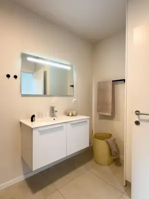 a white bathroom with a sink and a mirror at Genk Central Apartment in Genk