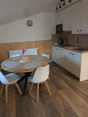 a kitchen with a wooden table and white chairs at B&B Hoeve Terwinghe in Gingelom