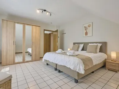 a bedroom with a large bed and a bathroom at Hesbein in Tongeren