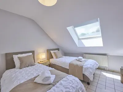 a attic bedroom with two beds and a window at Hesbein in Tongeren