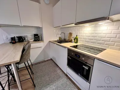 a kitchen with white cabinets and a table and a counter at Le coeur Liégeois - Hypercentre quartier piéton in Liège