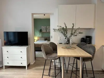 a living room with a table with chairs and a television at Le coeur Liégeois - Hypercentre quartier piéton in Liège