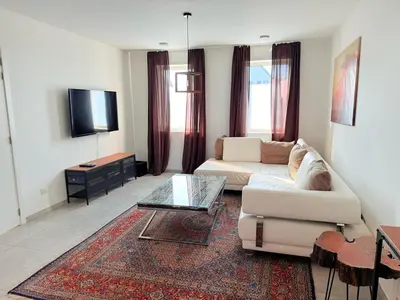 a living room with a white couch and a tv at House with garden, fireplace and hot tub in Kinrooi