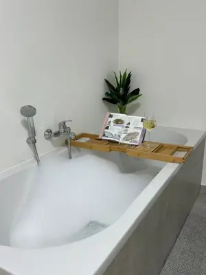 a bath tub with a book and a glass of wine at House with garden, fireplace and hot tub in Kinrooi