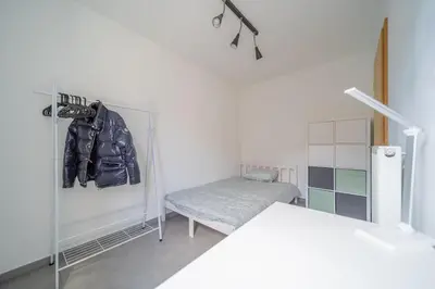 a white room with a chair and a closet at Liège 3 Bedroom Apartment, Quiet and Central in Liège