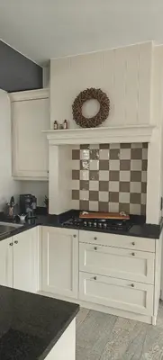 a kitchen with white cabinets and a black counter top at holiday home Zonnestraal in Zonhoven
