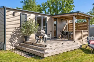 a cabin with a deck with a table and chairs at Holiday home La Casetta in Kinrooi