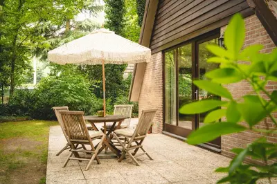a table and chairs with an umbrella on a patio at Boshuisje Rekem - Nilsson in Lanaken