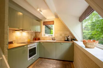 a kitchen with green cabinets and a window at Boshuisje Rekem - Nilsson in Lanaken