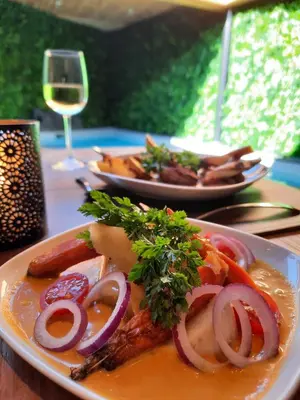 a plate of food on a table with a glass of wine at Clos des Thermes-Zanzibar in Liège