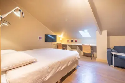 a bedroom with a bed and a desk and a television at Domein Marsnil in Heers