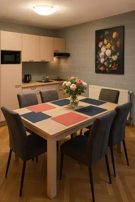 a dining room table with chairs and a vase of flowers on it at L'appart en gare in Welkenraedt