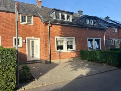 a brick house with a white door on a street at Cottage CaLoMa in Eupen
