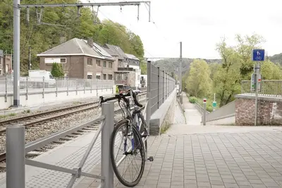 a bike is chained to a fence at a train station at Gîte d'artiste, Riverside in Tilff