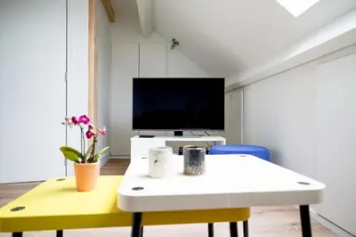 a living room with a white table and a tv at Gîte d'artiste, Riverside in Tilff