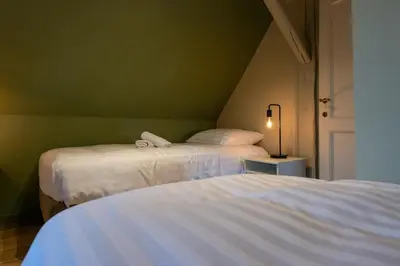 two beds in a room with green walls at Luxe Vacation Villa with swimming pool, 5 bedrooms in Houthalen-Helchteren