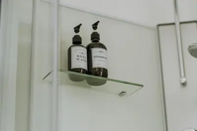 two bottles of wine sitting on a glass shelf in a shower at 1 bedroom apartment in Liège center, Place du Marche - 3rd floor in Liège