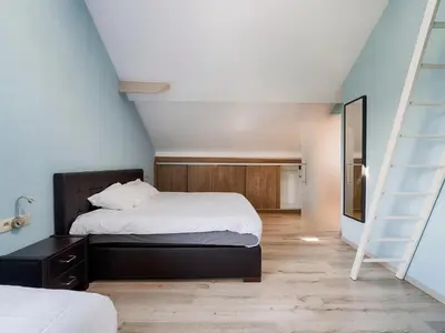 a bedroom with a large bed and a staircase at Villa Borgloon with Blossom Views and Jacuzzi in Borgloon