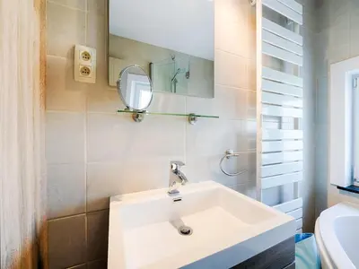a bathroom with a white sink and a mirror at Villa Borgloon with Blossom Views and Jacuzzi in Borgloon