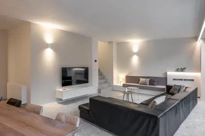 a living room with a black couch and a tv at Borgraaf - Palazzio in Borgloon