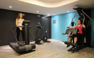 a man and woman riding exercise bikes in a gym at Le spot Central securisé sauna rooftop in Liège