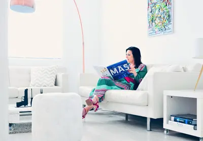 a woman sitting on a couch reading a magazine at BEEEP Stay in Hasselt