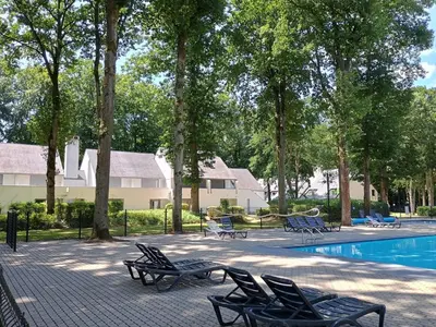 a group of chairs sitting next to a swimming pool at Studio Eik 105 at the pool in nature domain in Houthalen-Helchteren